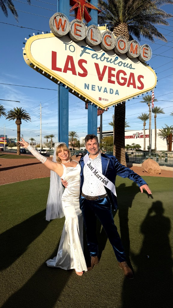 Couple at the Welcome to Las Vegas sign with Just Married sash
